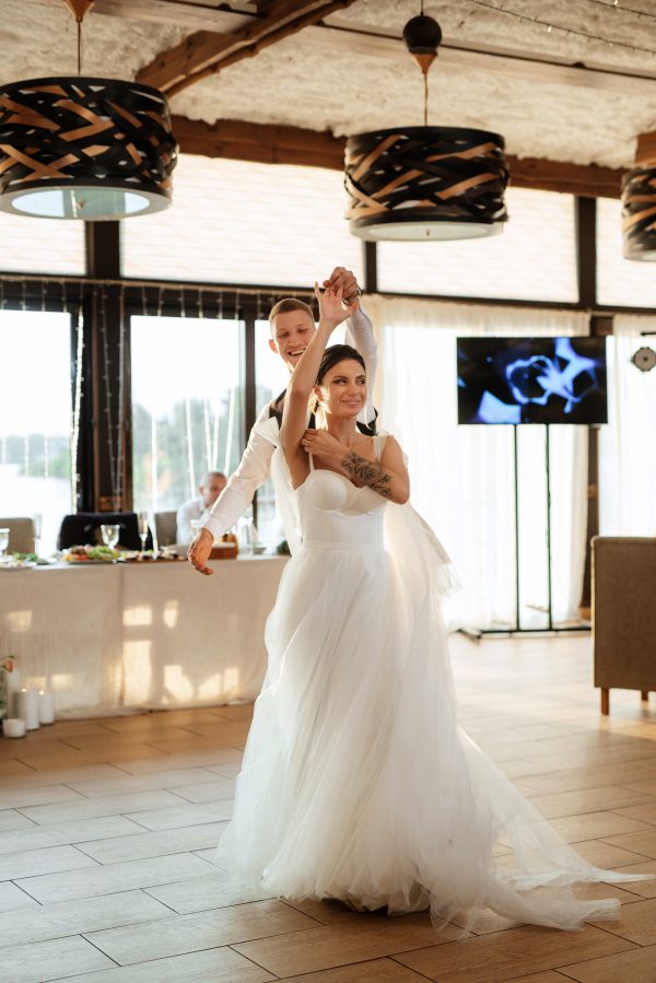 the first wedding dance of the bride and groom inside the restaurant hall in sunset light